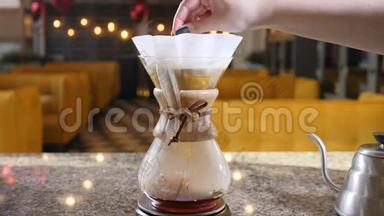 现代咖啡制作方法。 靠近一个咖啡师做手工煮咖啡。 在纸过滤机中搅拌研磨咖啡
