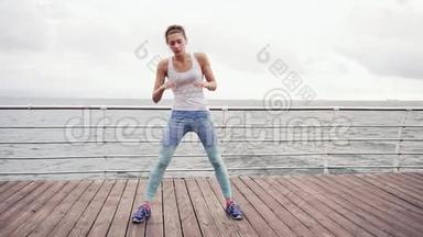 跑步的女人伸展身体做弓。 健身女运动员在海滩上放松，在做有氧运动前做热身运动