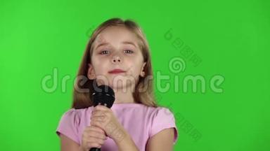 童女将歌曲唱入话筒.. 绿色屏幕。 慢动作