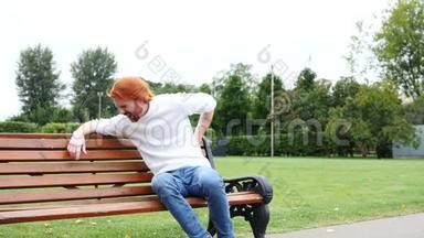 <strong>背部疼痛</strong>、脊柱<strong>疼痛</strong>、坐在长凳上、红胡子和头发上的疲惫的人