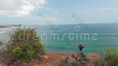 4K航天无人机镜头，快乐健康浪漫的女人坐在悬崖上。 美的出行运动理念.. 巴厘