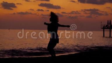 幸福苗条的女人在日落后的傍晚在海边跳跃，双手<strong>腾空</strong>而起