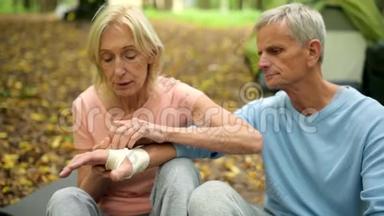 有爱心的老妇人用绷带包扎丈夫的手