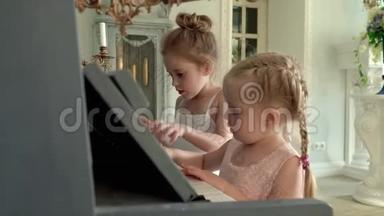 两个小女孩弹钢琴。 两个金发小姑娘学弹钢琴