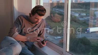 男人看着手机，在夕阳下坐在阳台上的<strong>社交网络</strong>里翻着带子。