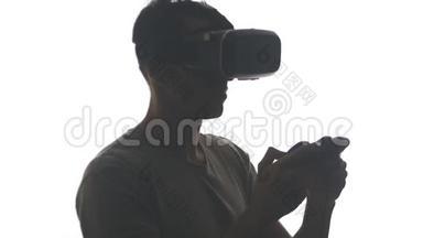 年轻人戴vr眼镜玩游戏的剪影。 他有使用虚拟现实头盔的经验