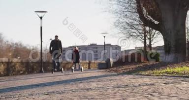 女儿的孩子和她的父亲在城里骑着西格威。 现代未来运输技术.. 积极的家庭。 公园人行道