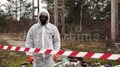 穿着生物危险服和防毒面具的人站在满是废物的地方的条纹后面