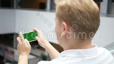 这家伙在智能手机上玩射击和比赛。 绿色手机屏幕键控。 一个男人