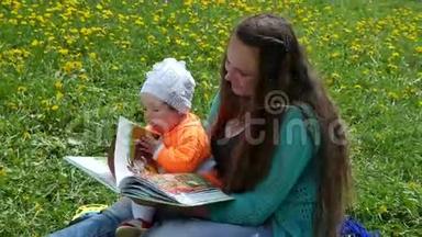 一个快乐的孩子和他的家人在蒲公英的春天的小路上。 坐在母亲`腿上读一本书。
