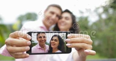 <strong>情侣</strong>手持手机拍照拥抱热带森林的<strong>亲吻</strong>户外，年轻人和女人
