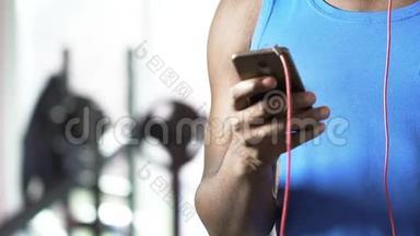 混合种族的人<strong>滚动</strong>手机<strong>屏幕</strong>，在锻炼前选择音乐