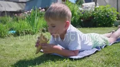 一个小男孩躺在草坪上，高兴地吃冰淇淋。 炎炎夏日，冷甜甜点