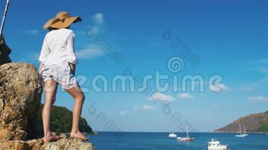 一个戴帽子的孤独女孩正沿着岛屿海岸线散步。 日出时热带天堂海滩