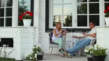一对夫妇正在一间避暑别墅的后院喝茶