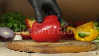 黑手套厨师手里拿着多汁的红椒，红椒放在一块木板上，上面有一个切割的脊骨