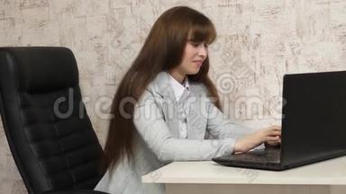 漂亮的女商人在笔记本电脑上写商务信函。 在电脑办公室工作的年轻女孩