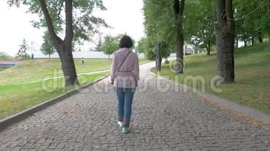 一个戴着太阳镜的<strong>中年妇女</strong>在公园里慢慢地走着..