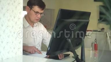 一个穿白衬衫的男人在他的办公室里的电脑后面工作