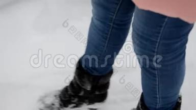特写<strong>黑色</strong>靴子在雪地里行走.. 穿着粉红色<strong>羽绒服</strong>的女孩在白雪覆盖的森林乡间小屋小径上。 冬季