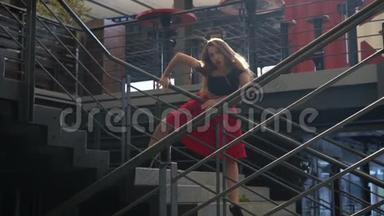 神秘的女孩在阳光下，穿着红色的裙子，黑色的顶部在商场的楼梯中间，慢动作