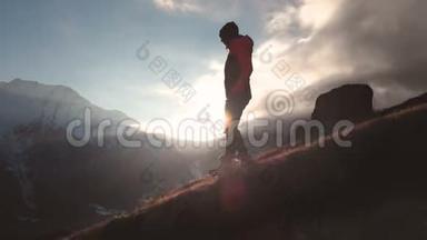在美丽的日落中，一个女孩走在山的边缘，作为一个剪影的史诗般的空中景色