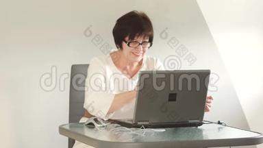 在办公室工作的女商人。 仔细看着眼镜上方的笔记本电脑屏幕。 微笑商务小姐