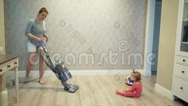 妈妈用<strong>吸尘器</strong>清理地板上的灰尘，一个小孩子`她的女儿正在附近玩耍。