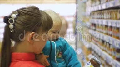 可爱的白种人妇女选择婴儿食品在超市抱着婴儿怀里。 妈妈和宝宝的特写镜头