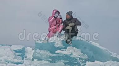 在冰封的湖面上，年轻夫妇在冬天散步时玩得很开心。 情侣们坐在蓝色的<strong>大冰块</strong>上