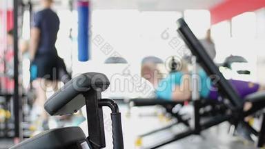 在健身房积极锻炼，强壮的男人做哑铃练习，教练训练女人