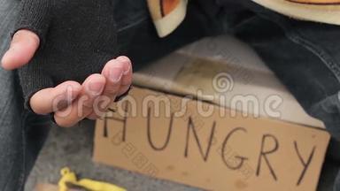 无家可归的人伸出颤抖的手乞讨，贫穷和痛苦
