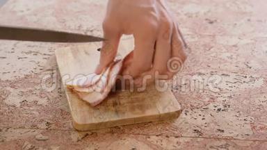 人把猪肉牛腩培根切成小块放在木板上。