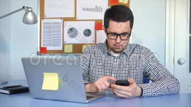 在办公室工作的人带着笔记本电脑，他用智能<strong>手机查找</strong>信息。