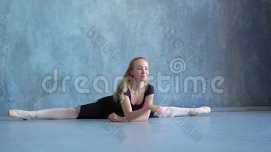 芭蕾舞女演员坐在芭蕾舞学校工作室镜头前的一根线上。 年轻女孩是芭蕾舞演员