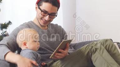 年轻的父亲和小儿子一起玩平板电脑圣诞节。
