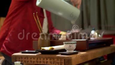 中国茶杯在锋利，背景上模糊了中国传统茶饮的过程。 主人