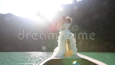 新娘和新郎之吻站在后光的长尾船上