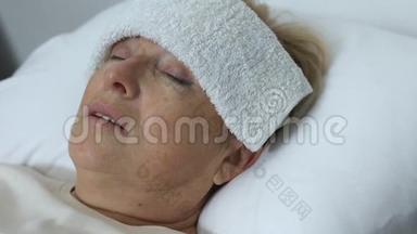 患感冒或流感的病老妇人，额头上有毛巾躺在床上