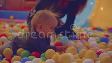 妈妈和金发小孩在带着小蛋蛋的干池里玩得开心