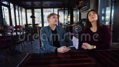 女友和<strong>男友</strong>带着智能手表，讨论自己的咖啡屋的设计，并用智能手机拍照。