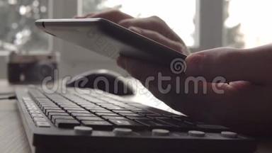 在坐电脑键盘和鼠标的时候，用平板电脑紧紧抓住年轻人的手。 自由摄影师