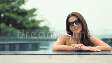 年轻漂亮的时尚女士在游泳池里摆着户外造型