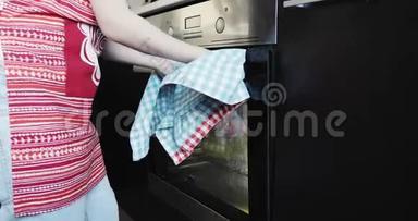 一个穿红色围裙的金发女孩从烤箱里拿出一个热馅饼。
