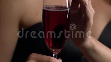 女人碰一杯酒。 红色的起泡葡萄酒装满了一杯。 女人喝一杯红酒。