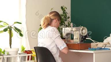 在家工作。 年轻的金发女人在明亮的房间里用打字机缝衣服