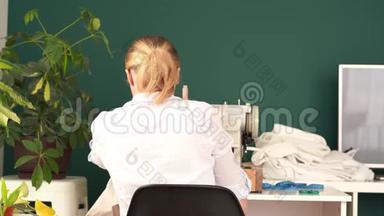 在家工作。 年轻的金发女人在明亮的房间里用打字机缝衣服