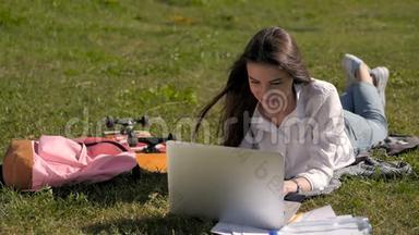 在大学校园公园用笔记本电脑工作的学生女孩的正面景色