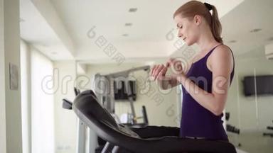 漂亮的适合年轻女子在健身房做<strong>运动</strong>在跑步轨道。 使用智能手表，检查<strong>生命</strong>体征