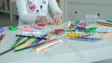 快乐的小女孩玩<strong>橡皮泥</strong>，雕刻一个图形，桌面上是图形和彩色铅笔，